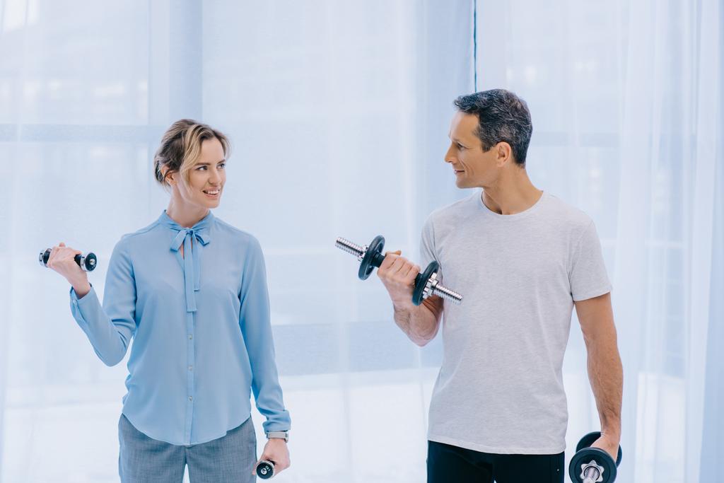 businesswoman and her personal trainer working out with dumbbells at office - Photo, Image