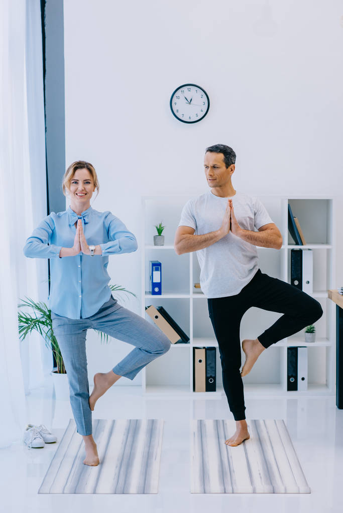 mulher de negócios em forma com seu treinador praticando ioga em pose de árvore no escritório
 - Foto, Imagem