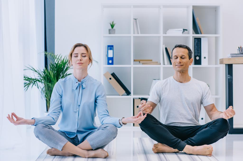 Geschäftsfrau meditiert mit ihrem Trainer in Lotus-Pose im Büro - Foto, Bild