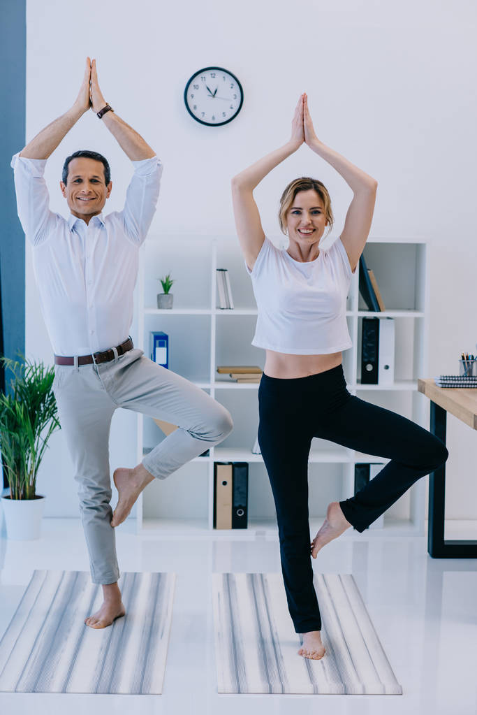 businessman with his trainer practicing yoga in tree pose at office - Photo, Image
