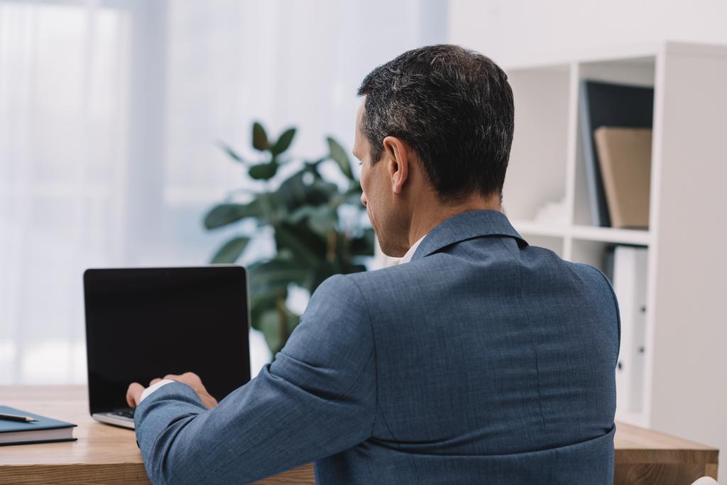 vue arrière d'un homme d'affaires mature utilisant un ordinateur portable sur le lieu de travail
 - Photo, image