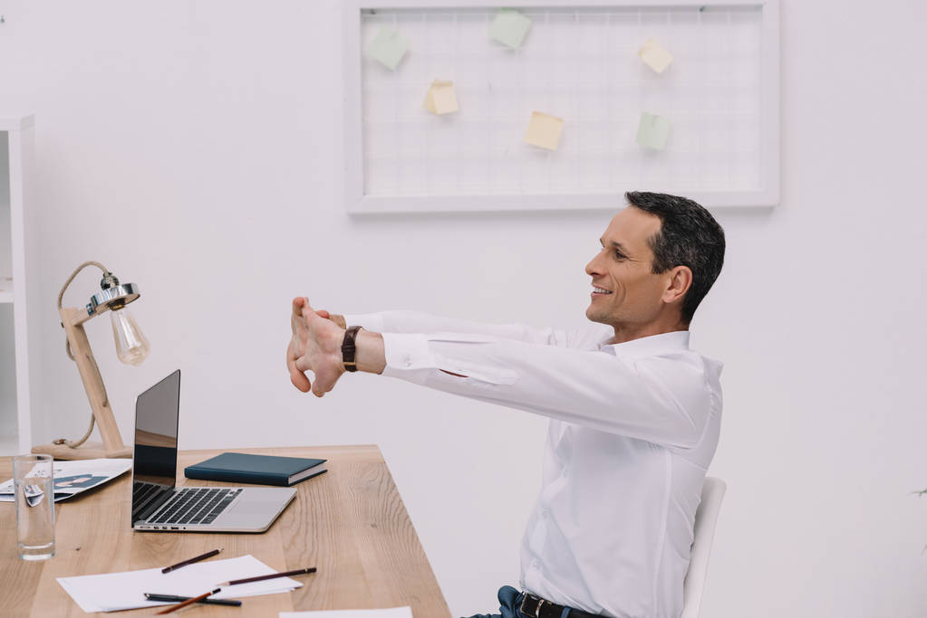 красивый взрослый бизнесмен протягивает руки в офисе
 - Фото, изображение