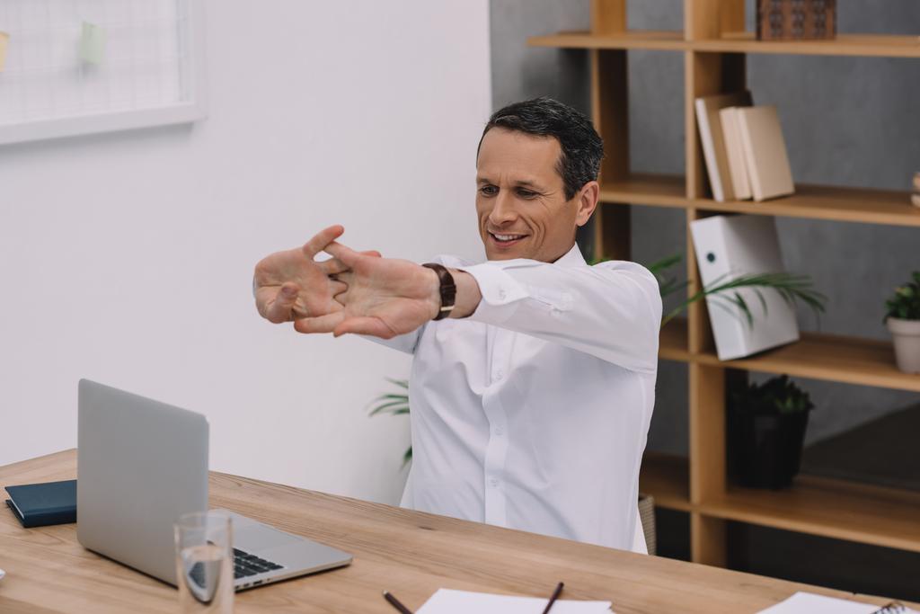 красивий зрілий бізнесмен розтягує руки в офісі
 - Фото, зображення