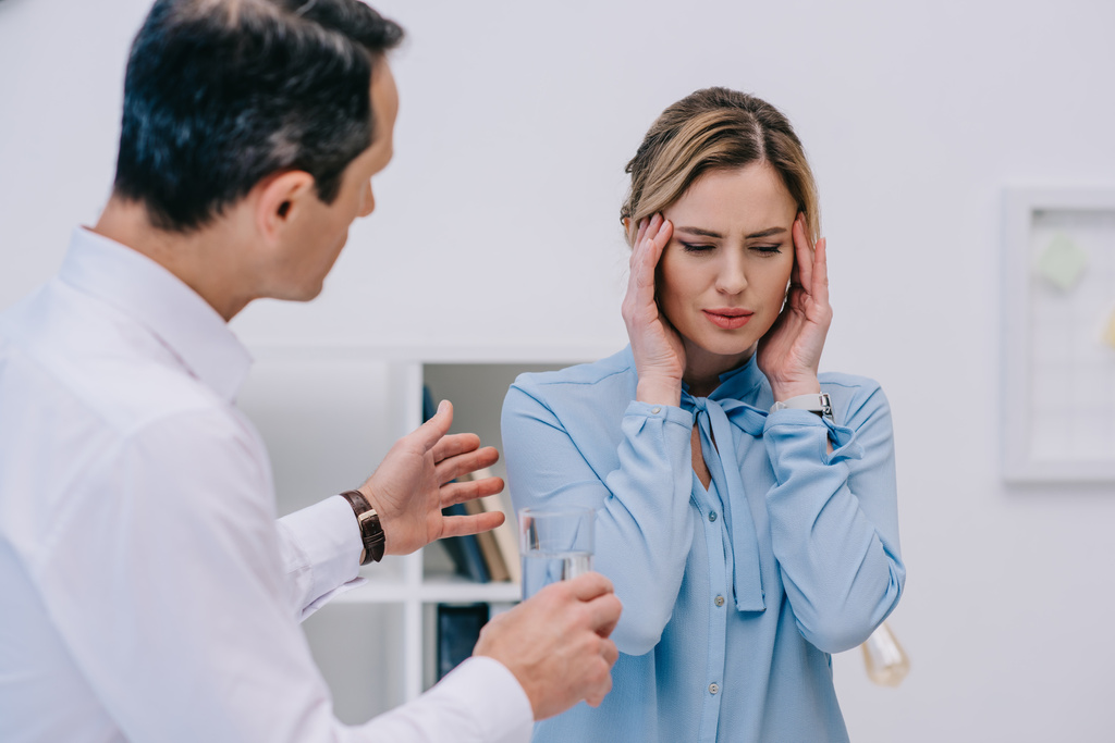 бизнесвумен страдает головной болью, а ее коллега пытается помочь ей в офисе
 - Фото, изображение