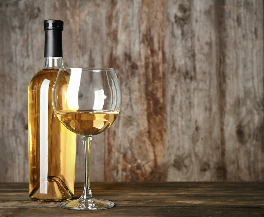 Şişe ve cam ahşap masa üzerinde beyaz şarap ile - Fotoğraf, Görsel