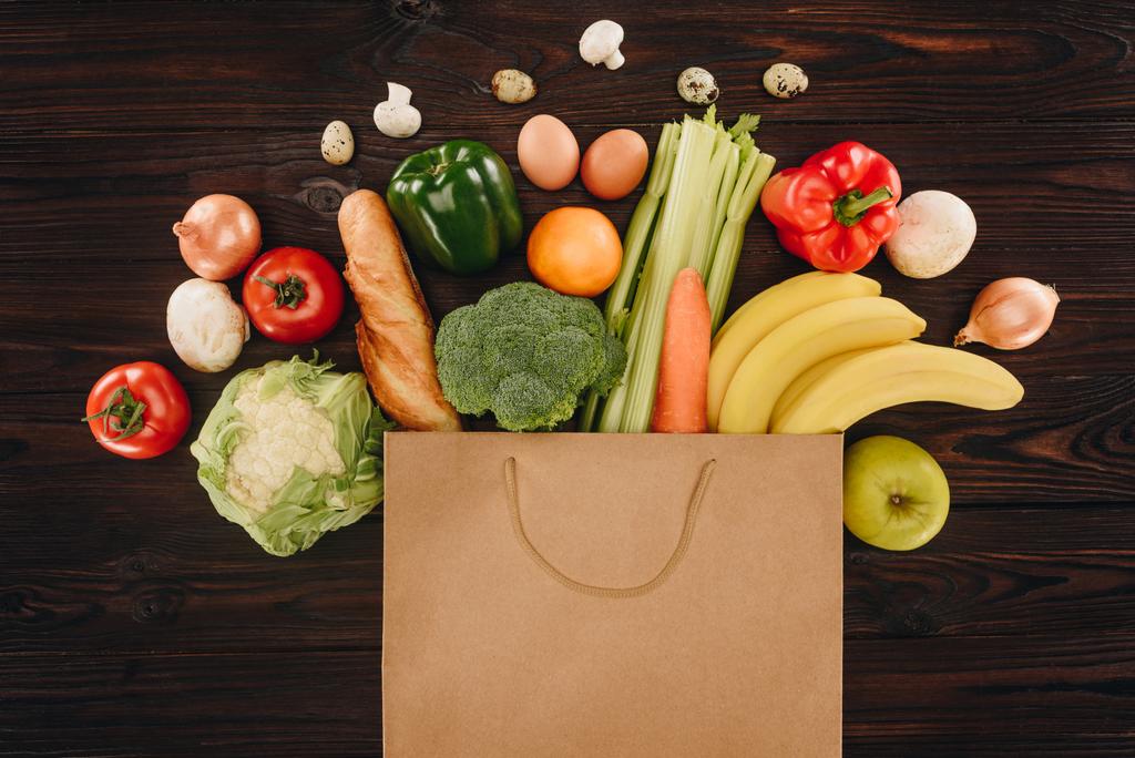 vista superior de diferentes verduras y frutas en bolsa de papel sobre mesa de madera, concepto de supermercado
 - Foto, imagen