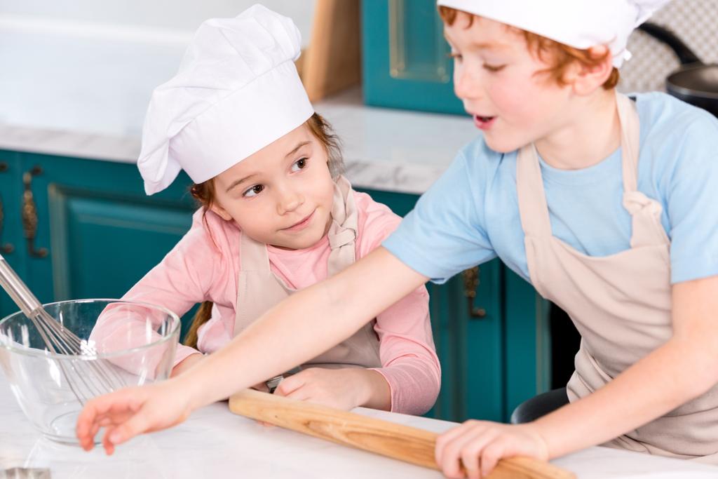 милые маленькие дети в фартуках готовят вместе на кухне
 - Фото, изображение