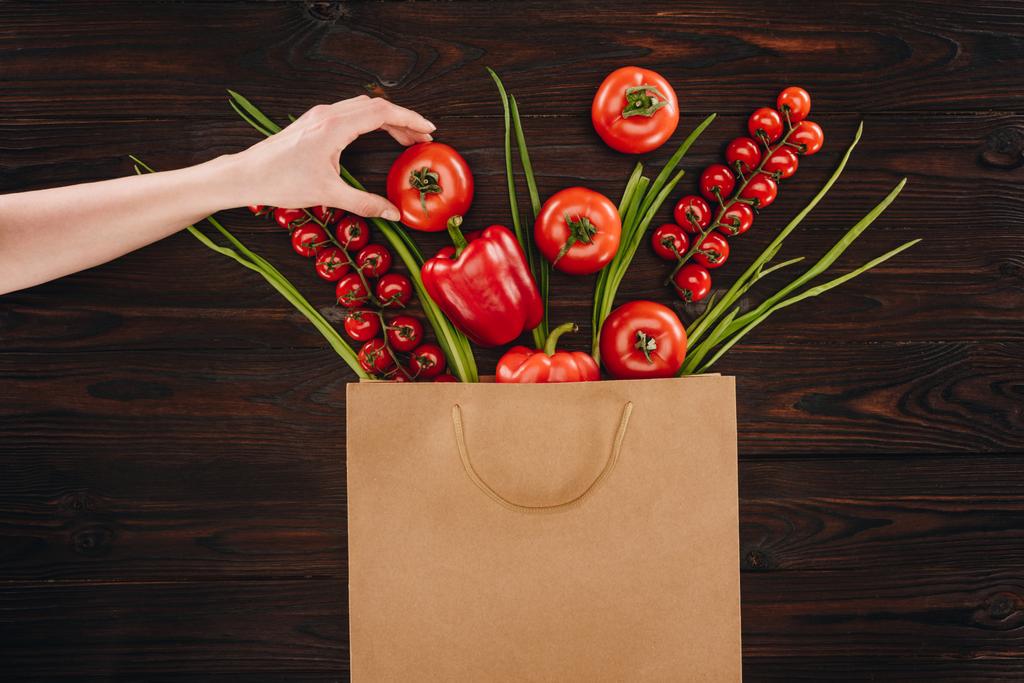 abgeschnittenes Bild von Mädchen, das Tomate aus Einkaufstasche nimmt - Foto, Bild
