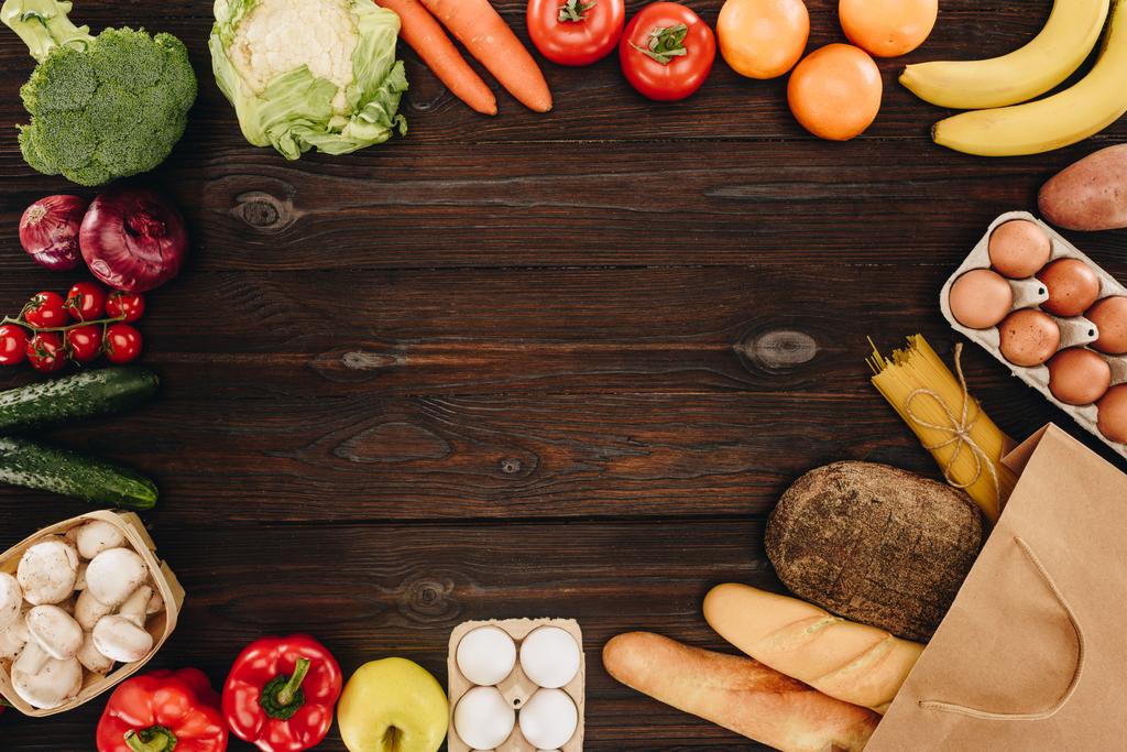 Blick von oben auf Gemüse und Obst mit Brot und Nudeln auf Holztisch, Lebensmittelkonzept - Foto, Bild