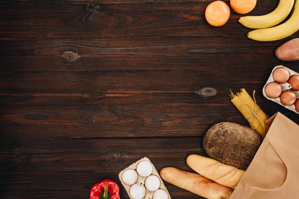 Draufsicht auf Brot mit Eiern und Gemüse mit Früchten auf Holztisch - Foto, Bild