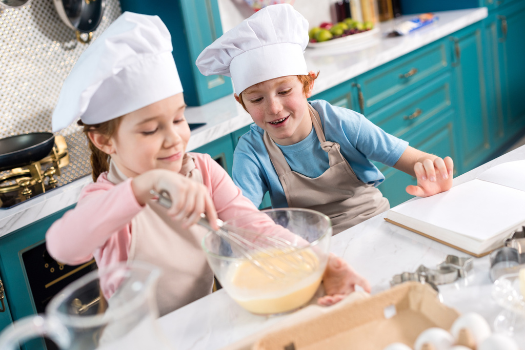 szczęśliwe dzieci w kapeluszach szefa kuchni, wyrabiania ciasta w kuchni - Zdjęcie, obraz