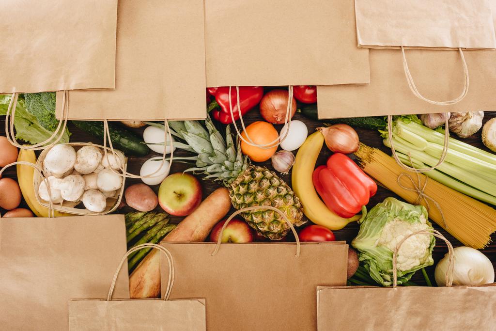 Ansicht von Einkaufstaschen mit Gemüse und Obst auf Holztisch - Foto, Bild