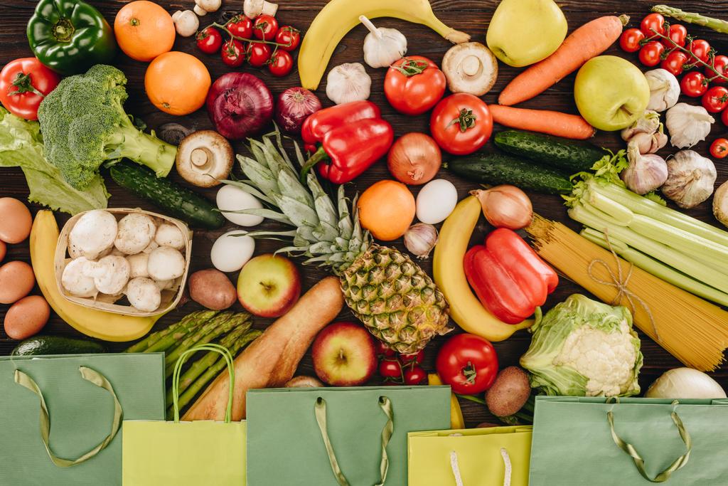 top view of vegetables and fruits with paper bags on wooden table - Photo, Image