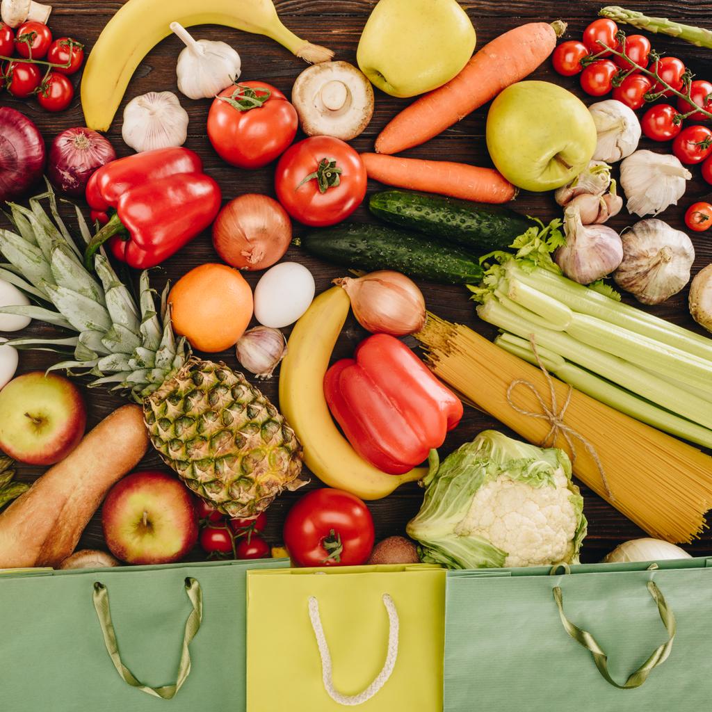 pohled shora zeleniny s ovocem a nákupní tašky na dřevěný stůl, koncept s potravinami - Fotografie, Obrázek