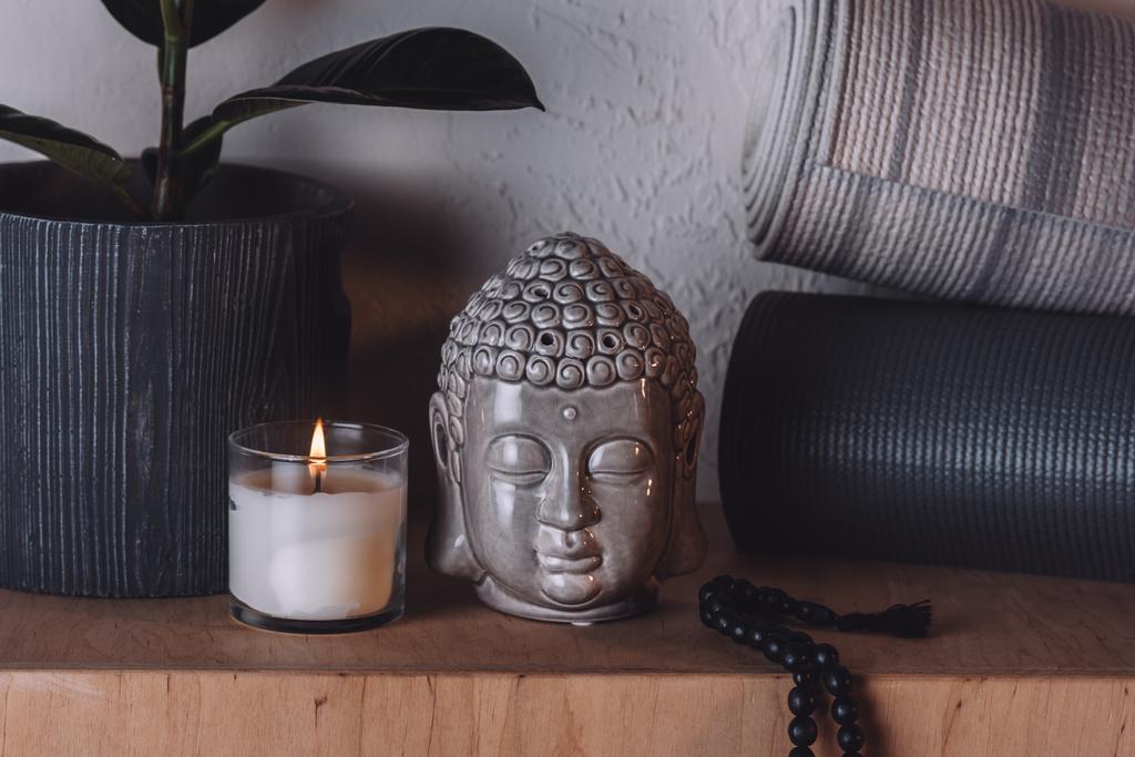 άγαλμα του Βούδα κεφάλι και γιόγκα χαλάκια στο ξύλινο ράφι  - Φωτογραφία, εικόνα