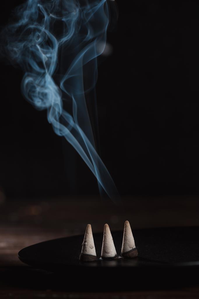 trois bâtons d'encens brûlants avec de la fumée sur la table
 - Photo, image