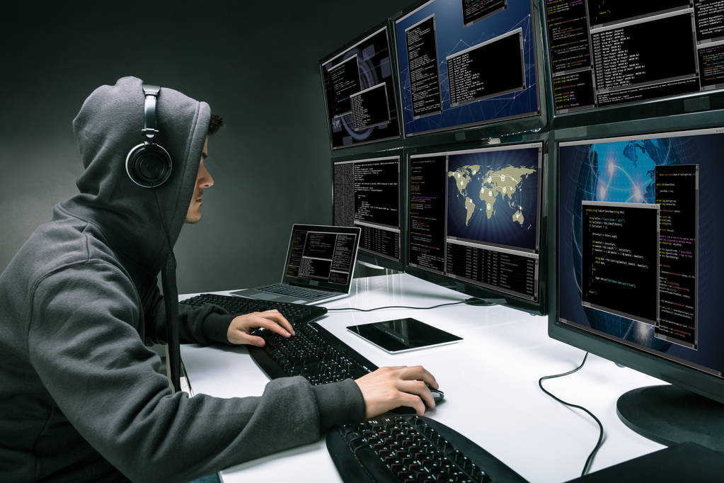Rückansicht eines Hackers, der mehrere Computer benutzt, um Daten im Büro zu stehlen - Foto, Bild