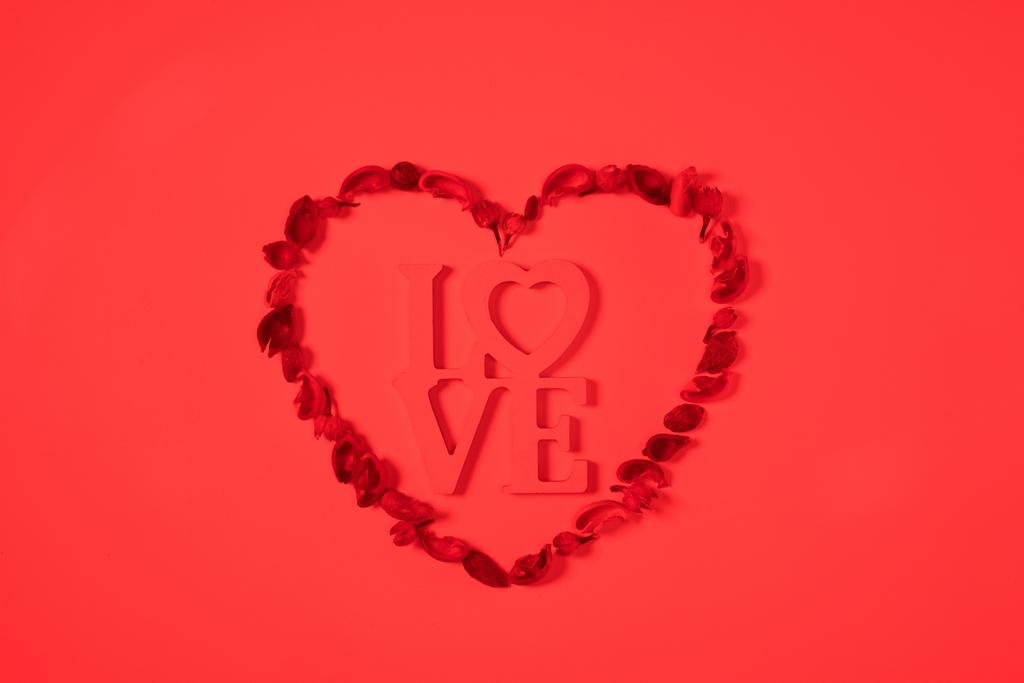 κάτοψη της καρδιάς από αποξηραμένα φρούτα με την λέξη αγάπη απομονώνονται σε κόκκινο - Φωτογραφία, εικόνα