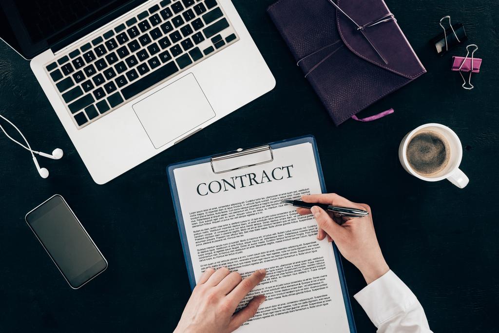обрізаний знімок контракту бізнес-леді на робочому місці ізольовано на чорному
 - Фото, зображення