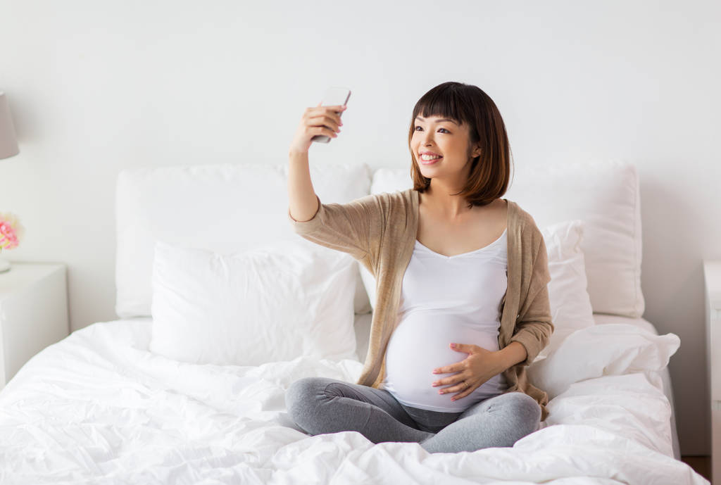 terhes nő vesz selfie, a smartphone otthon - Fotó, kép
