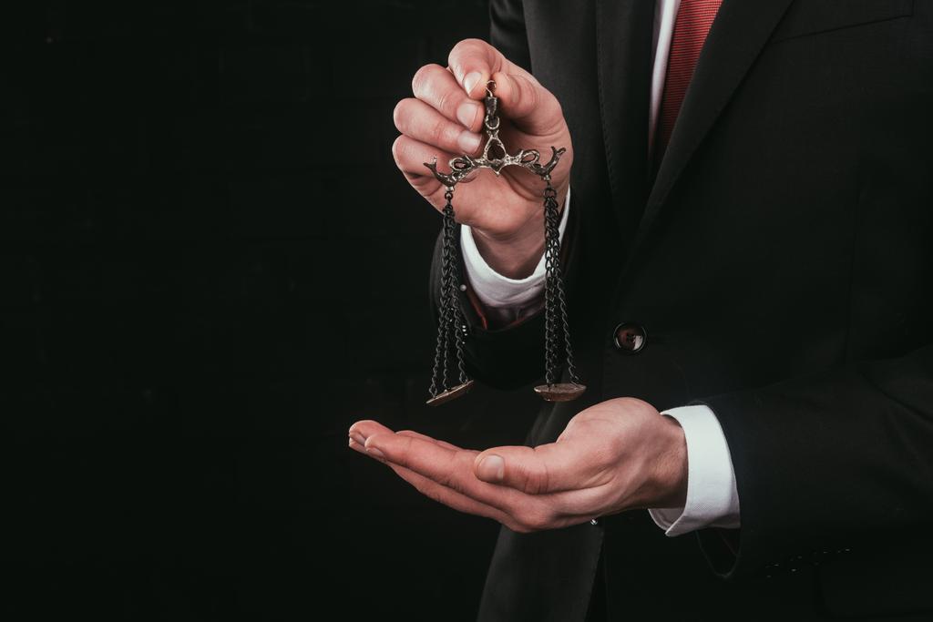 обрезанный снимок адвоката, держащего мини весы изолированные на черном
 - Фото, изображение