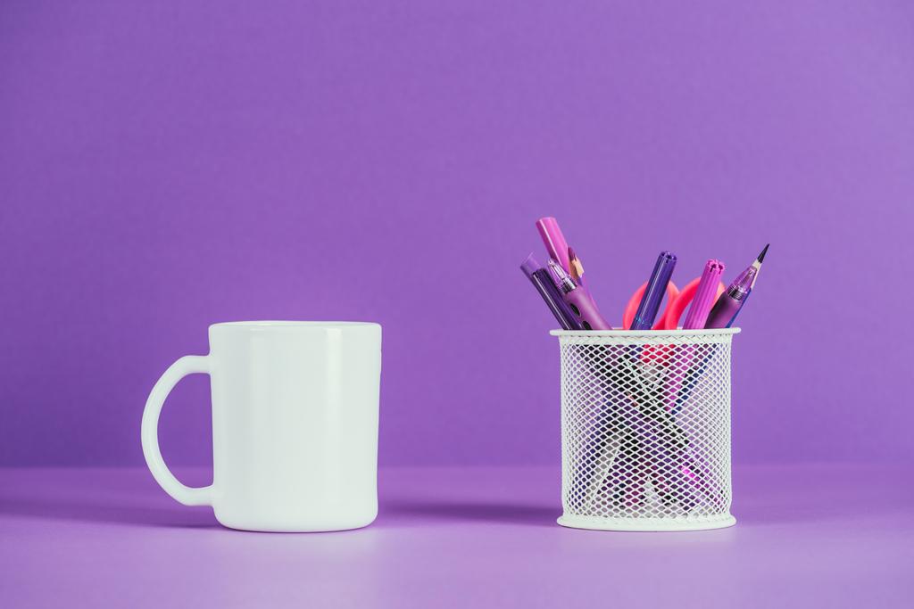 kupa és a tollat tartó lila felületen - Fotó, kép