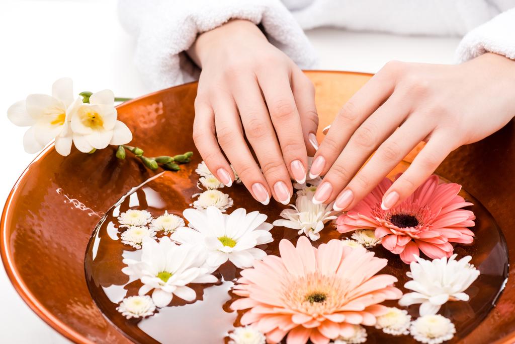 vista recortada de la mujer haciendo procedimiento de spa con flores en el salón de belleza, concepto de cuidado de uñas
 - Foto, imagen