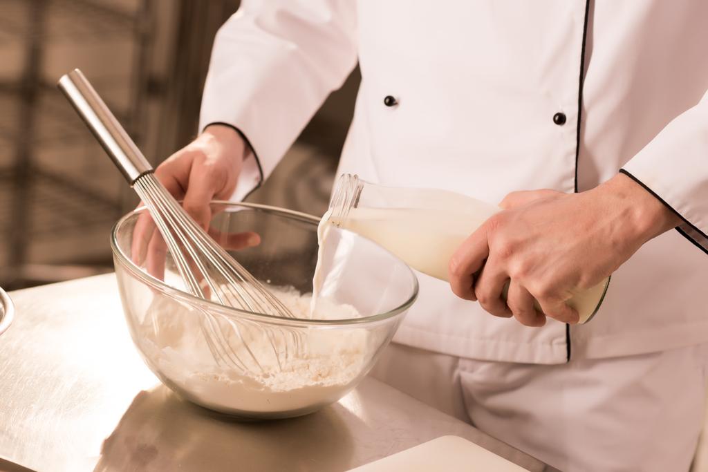частичный вид кондитера, добавляющего молоко в тесто на кухне ресторана
 - Фото, изображение