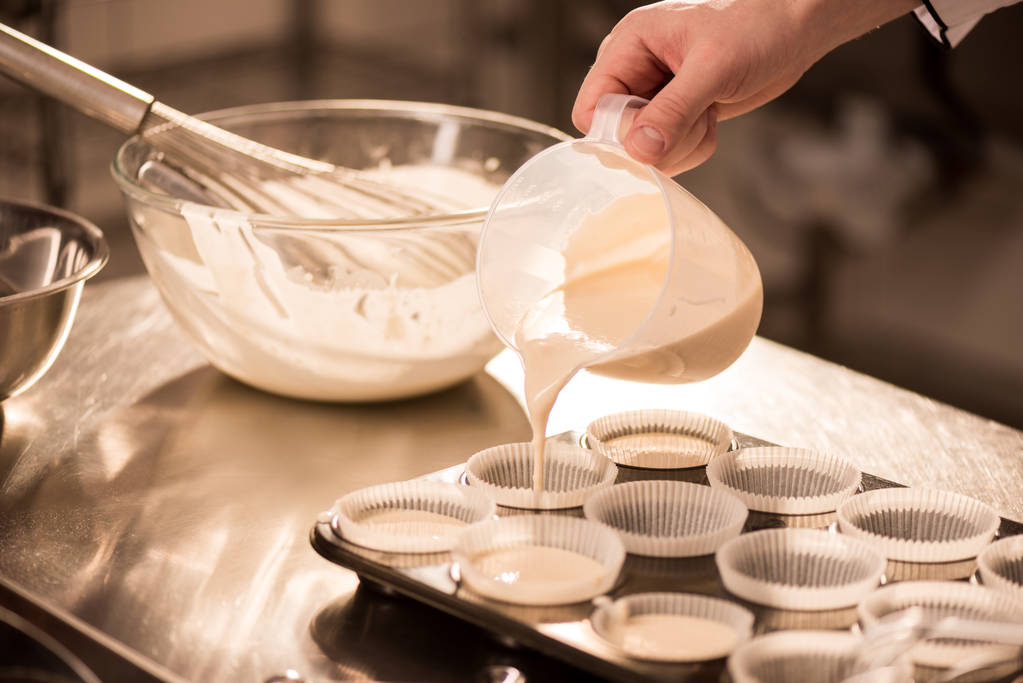 обрізаний дріб кондитерського виробу, що розливає тісто у форми для випічки
 - Фото, зображення