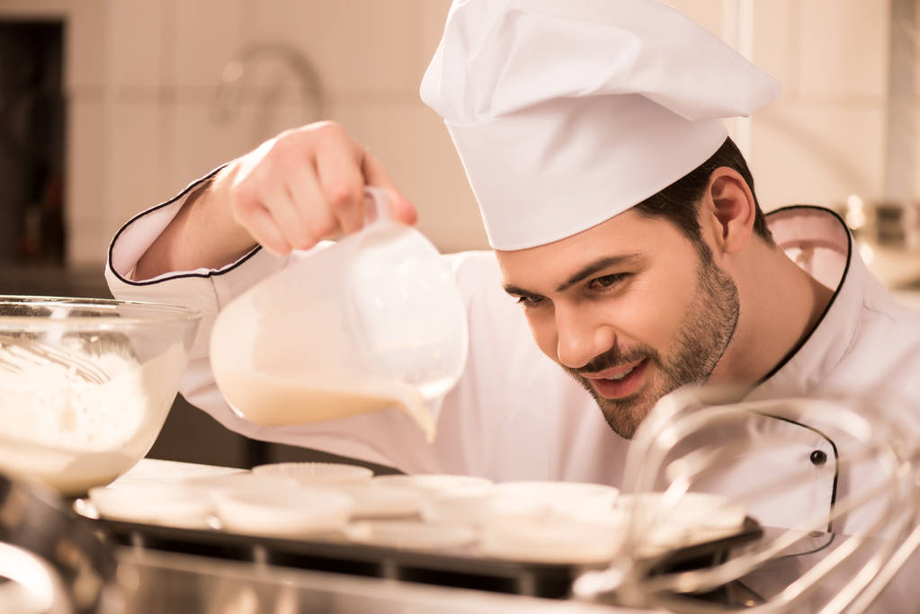 πορτρέτο του ζαχαροπλάστη ρίχνει ζύμη στο ψήσιμο φόρμες σε κουζίνα εστιατορίου - Φωτογραφία, εικόνα