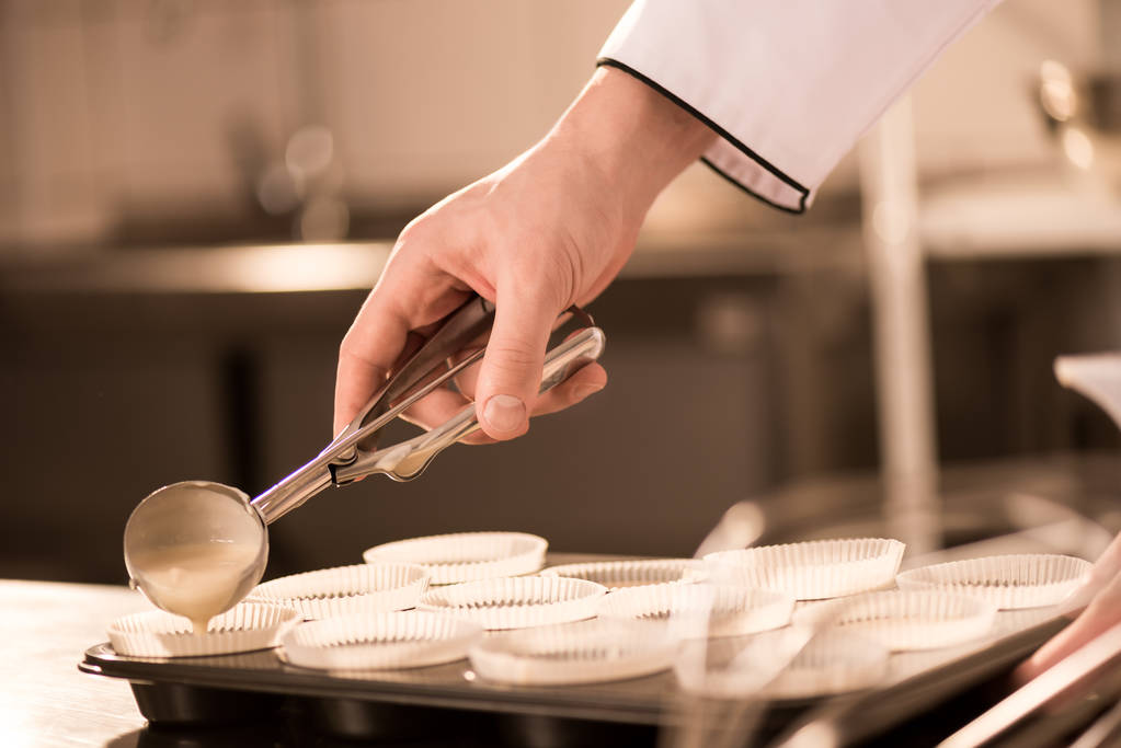 обрезанный кадр кондитера, наливающего тесто в хлебопекарные формы
 - Фото, изображение