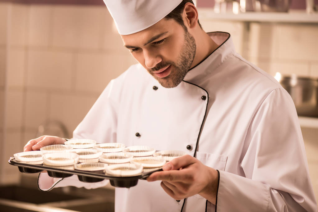 confectioner checking dough in baking forms in restaurant kitchen - Photo, Image