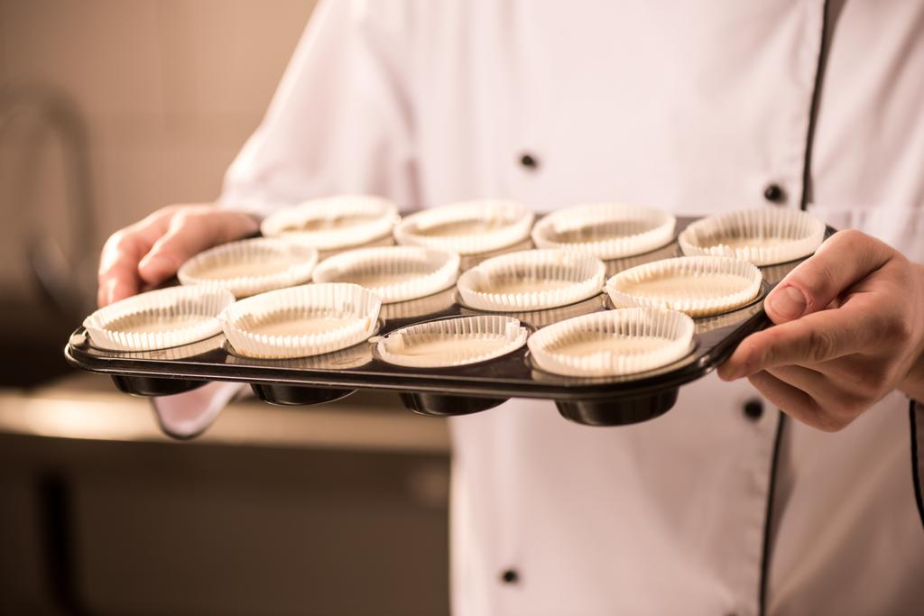 частковий вигляд кондитерського виробу з формами випічки, повними сирого тіста в руках
 - Фото, зображення