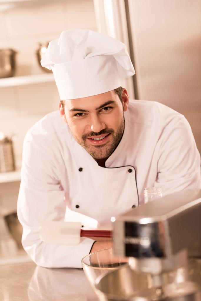 muotokuva hymyilevästä makeisesta keittiömestarin hatussa ravintolan keittiössä
 - Valokuva, kuva