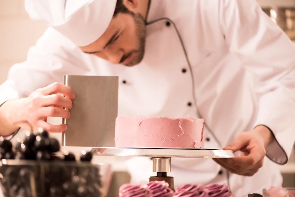 focused confectioner making sweet cake in restaurant kitchen - Photo, Image