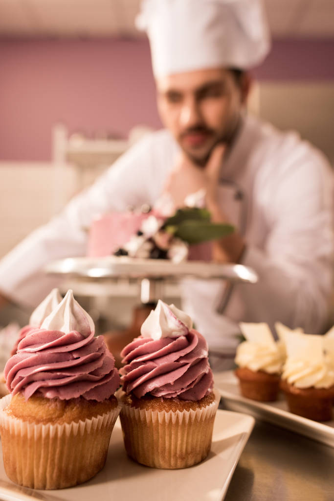 селективный фокус кексов и кондитеров, стоящих рядом торт на прилавке в кухне ресторана
 - Фото, изображение