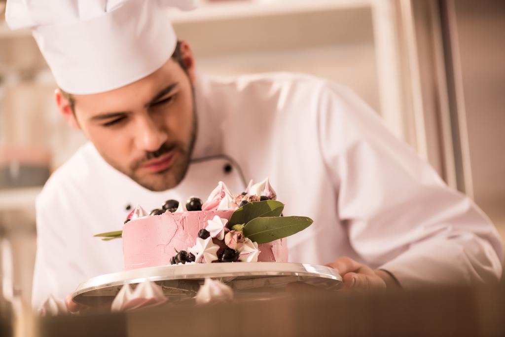Selektivní fokus cukrář pohledu na dort v ruce v kuchyni restaurace - Fotografie, Obrázek