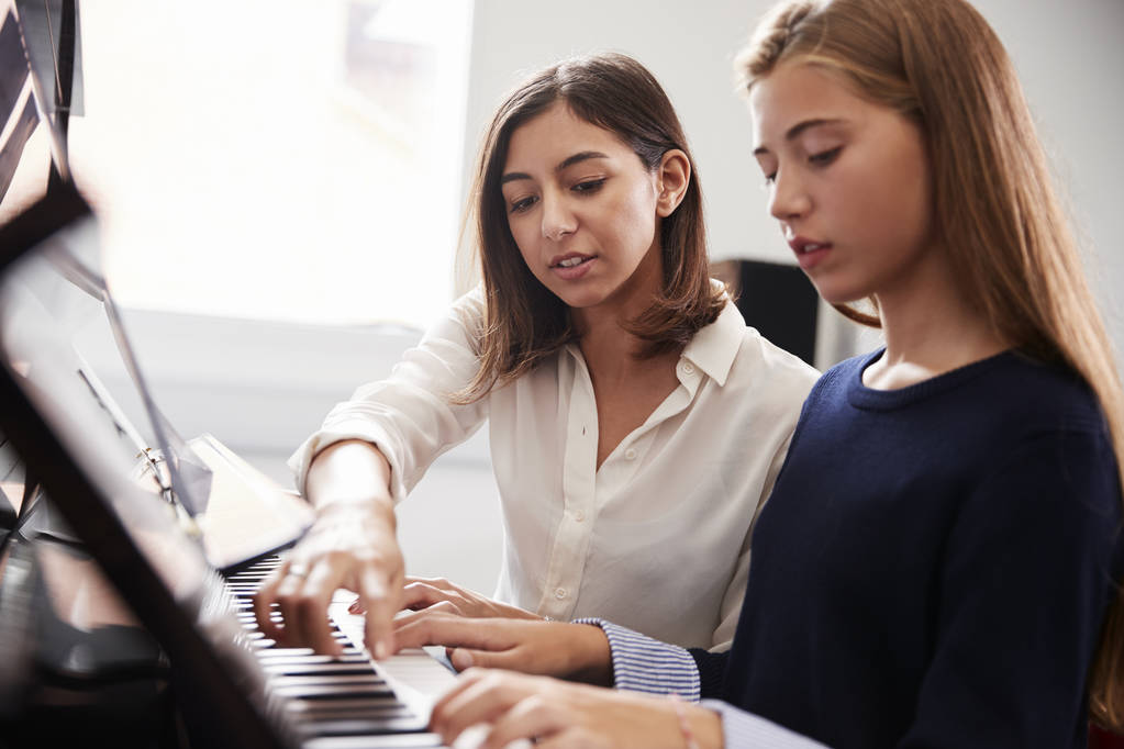 Allievo femminile con insegnante che suona il pianoforte a lezione di musica
 - Foto, immagini
