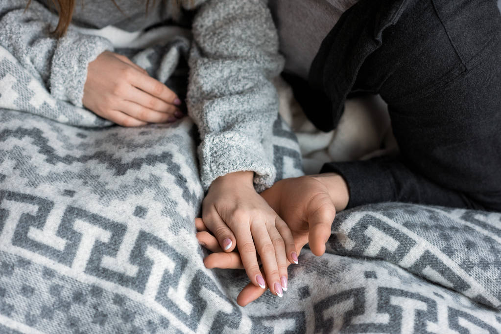 περικομμένη εικόνα του ζευγάρι κρατώντας τα χέρια στο κρεβάτι - Φωτογραφία, εικόνα