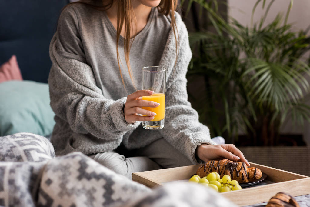 przycięte zdjęcie dziewczyna trzymając szklankę soku pomarańczowego na śniadanie  - Zdjęcie, obraz