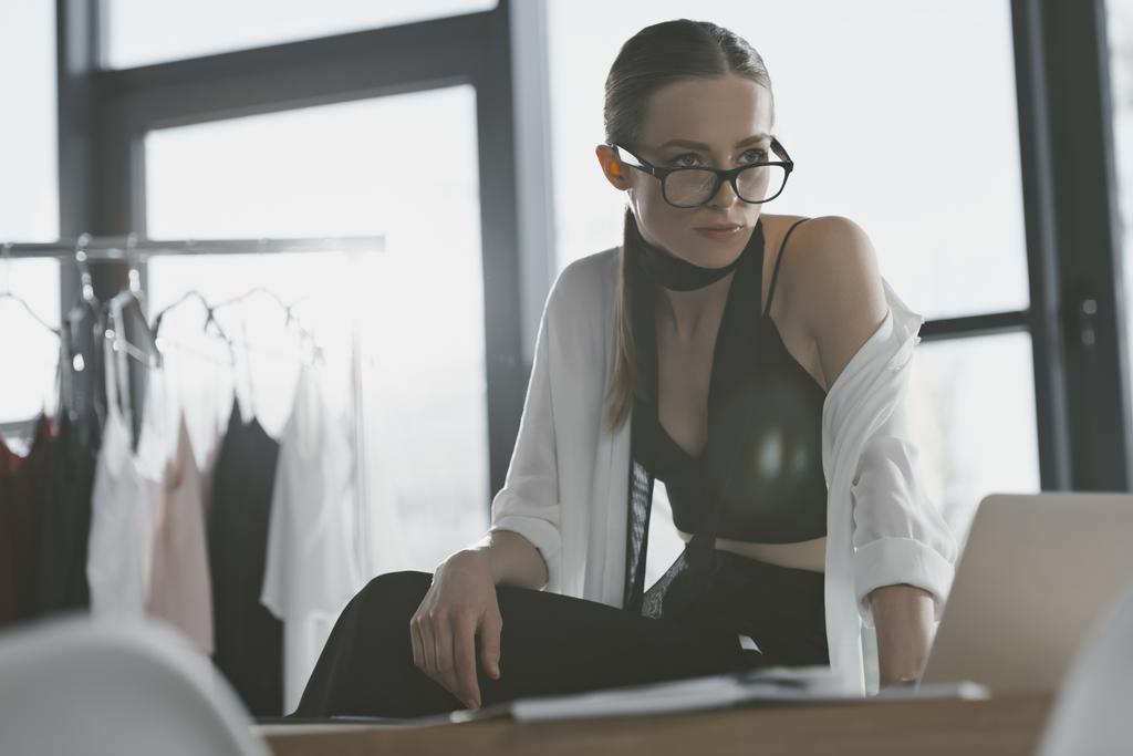 stylish fashion designer sitting on work desk at office - Photo, Image