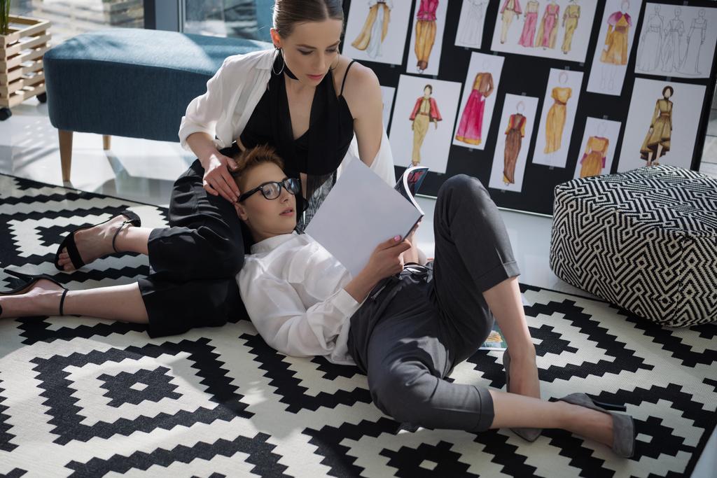 jóvenes diseñadores de moda lesbianas pareja trabajando juntos en el piso de la oficina
 - Foto, Imagen