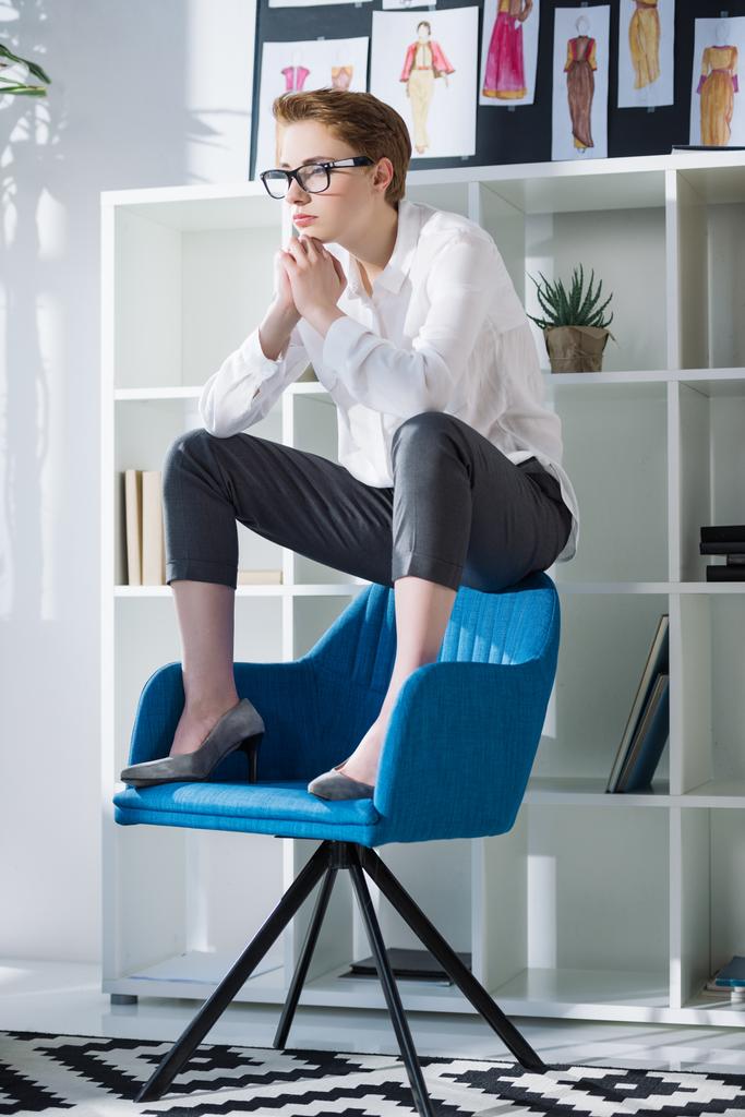 現代のオフィスで椅子に座って思慮深いスタイリッシュなファッション ・ デザイナー - 写真・画像