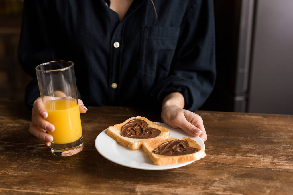 zugeschnittenes Bild eines Mädchens, das einen Teller mit Toasts mit Herzen aus Schokoladenpaste hält, Valentinstag-Konzept - Foto, Bild