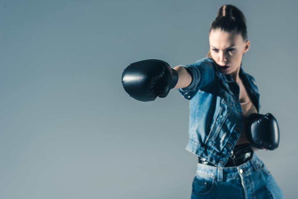selective focus of boxing girl in denim clothes, isolated on grey - Photo, Image