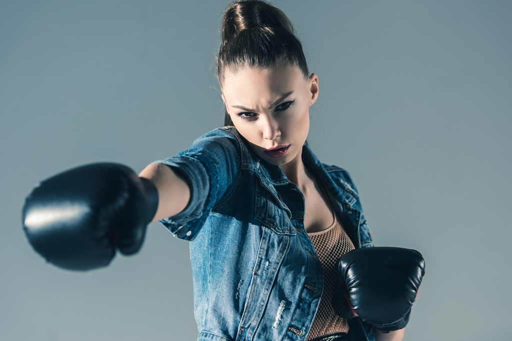 caucasian girl in denim clothes and boxing gloves, isolated on grey - Photo, Image