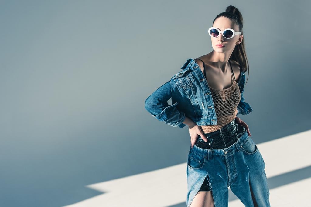 модная модель брюнетки позирует в джинсовом стиле и в солнечных очках
 - Фото, изображение
