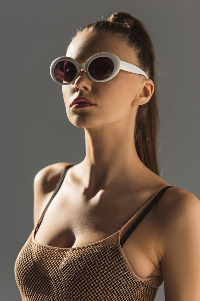 gyönyörű divatos lány pózol napszemüveg, elszigetelt szürke - Fotó, kép