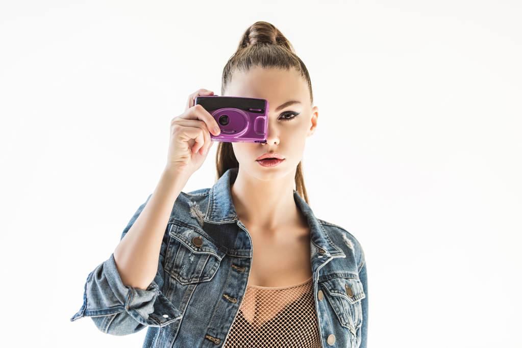 girl posing in denim clothes with retro camera, isolated on white - Photo, Image