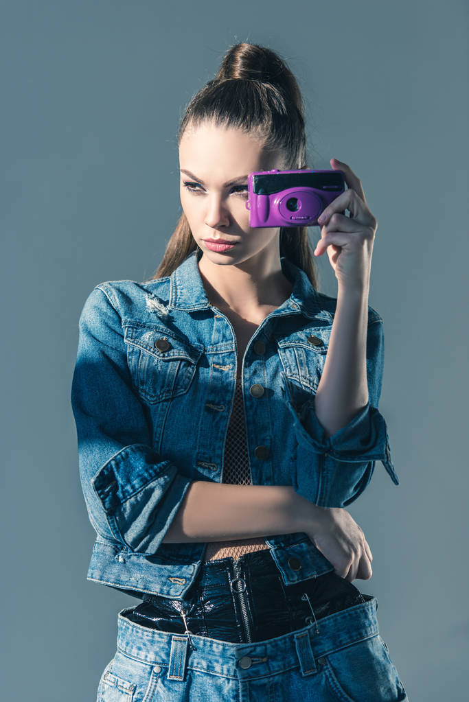 esmer kız gri izole retro kamera ile denim giysiler içinde poz - Fotoğraf, Görsel